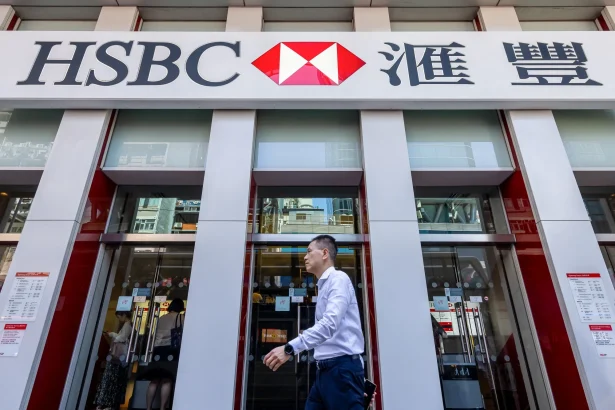 Front of an HSBC bank storefront with a large HSBC sign and Chinese characters; glass doors and pedestrians nearby.