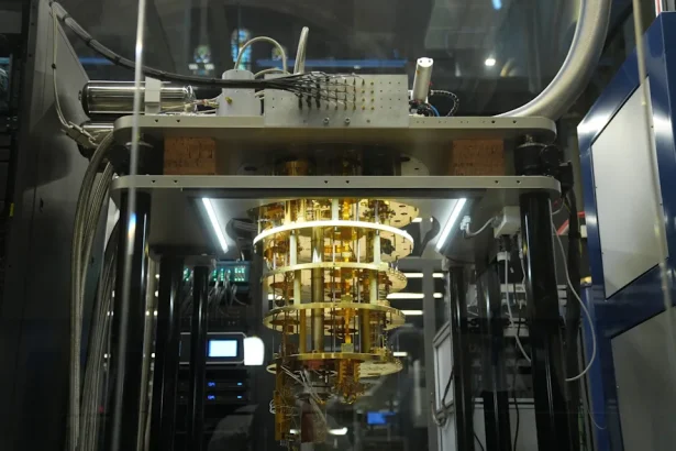 Gold-colored circular‑ringed instrument inside a glass enclosure in a lab, with cables and metal support structures around it.