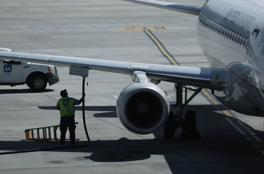 A ground crew worker refueling a commercial jet on the tarmac