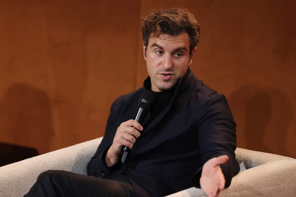 Airbnb CEO Brian Chesky speaking into a microphone while seated